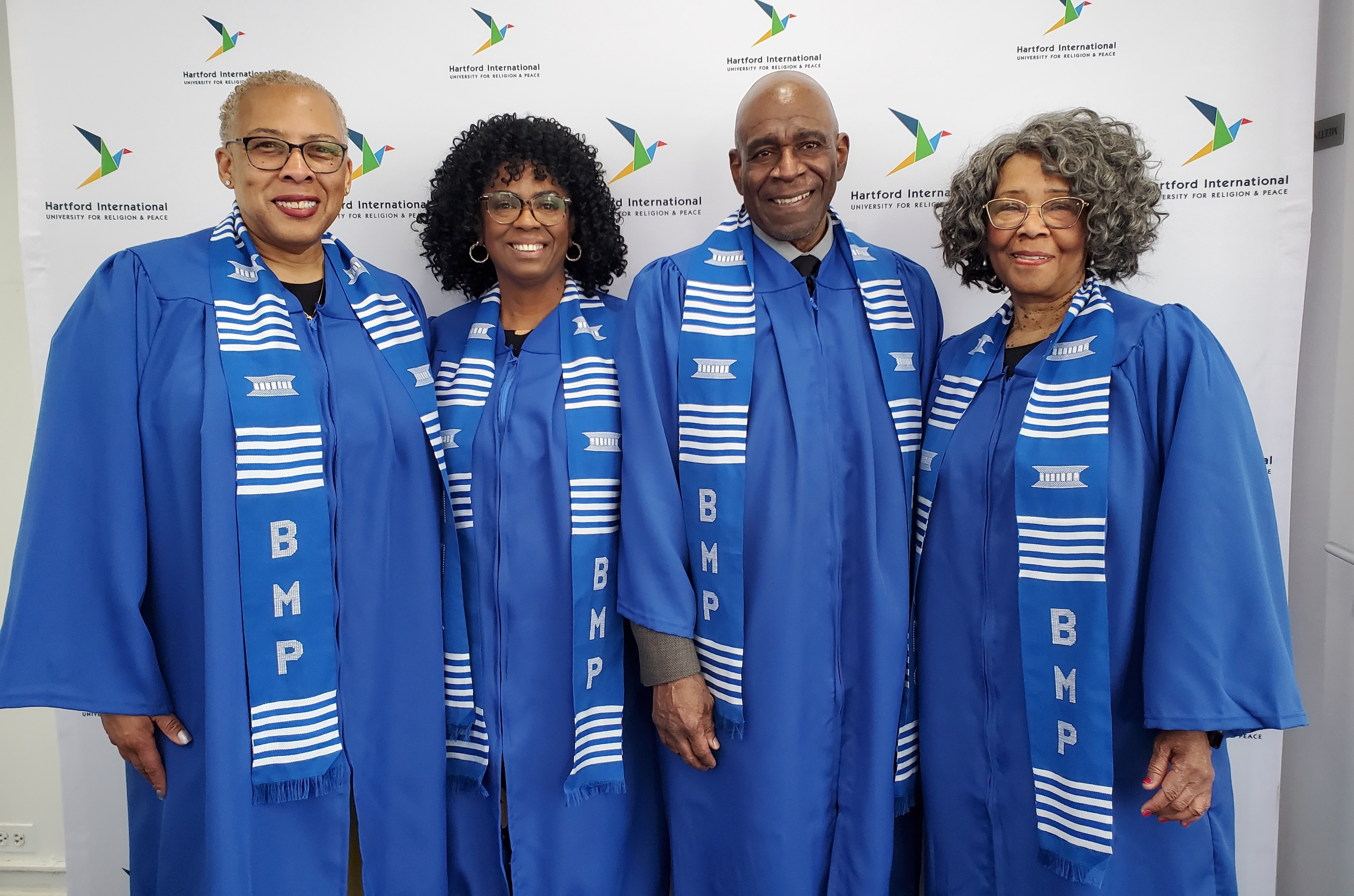 =Four people in blue graduation gowns