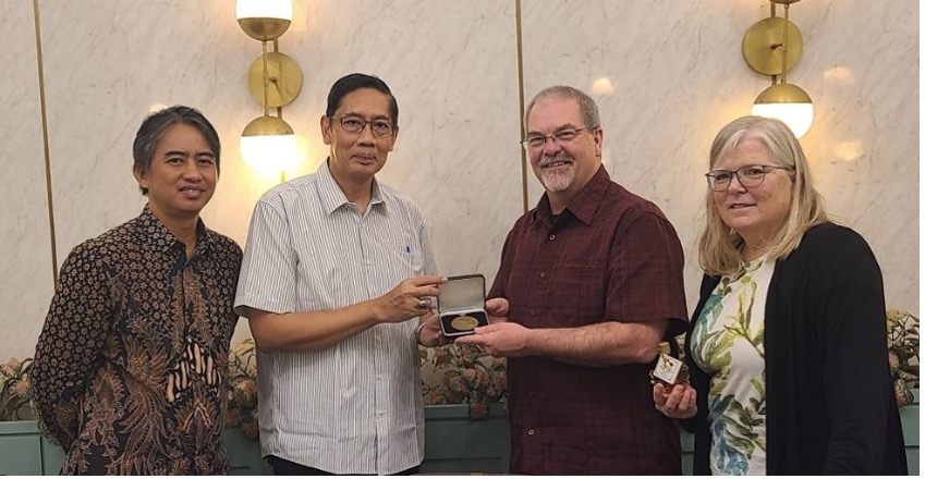 Man handing medal to another man