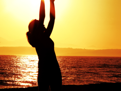 Silhouette of woman reaching toward sun