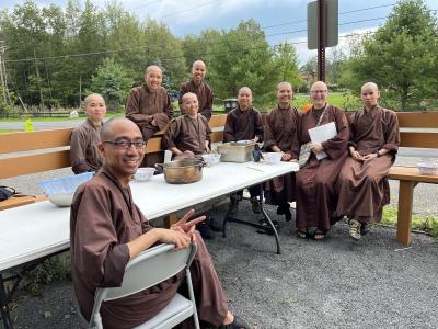 Group of Buddhist monks sitting around a table outdoors